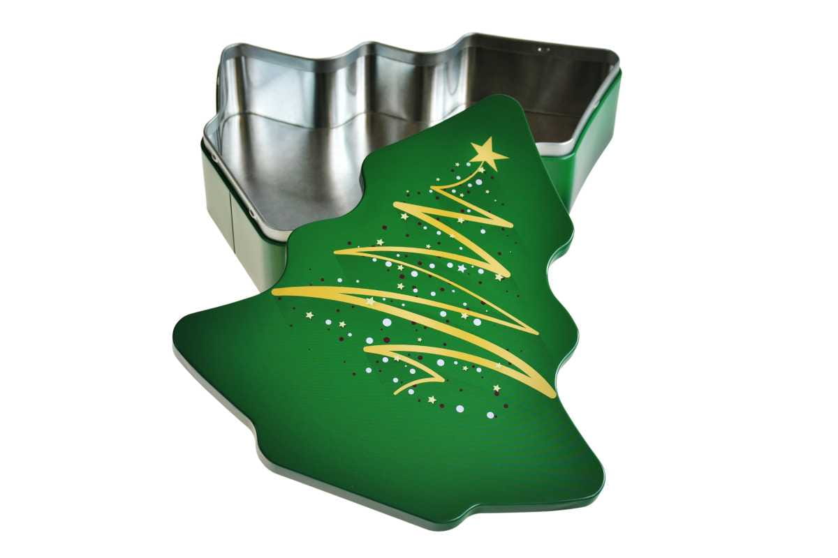 Geöffnete grüne Metalldose in Form eines Weihnachtsbaums mit abgenommenem Deckel, Innenraum sichtbar, fotografiert vor weißem Hintergrund.