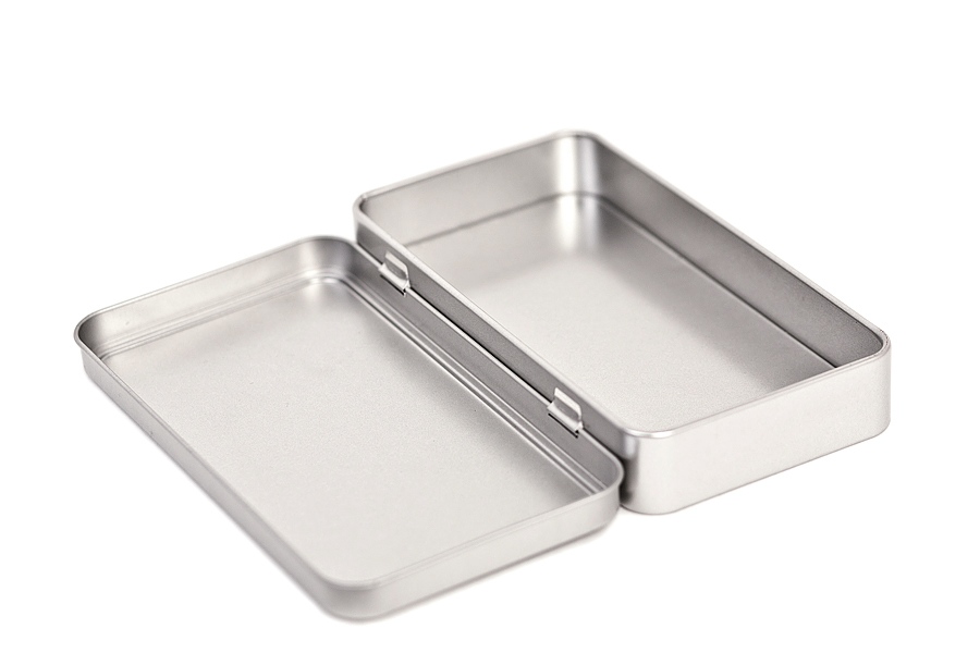 Geöffnete rechteckige Metallverpackung aus silberfarbenem Blech mit vollständig aufgeklapptem Scharnierdeckel, auf weißem Hintergrund fotografiert.